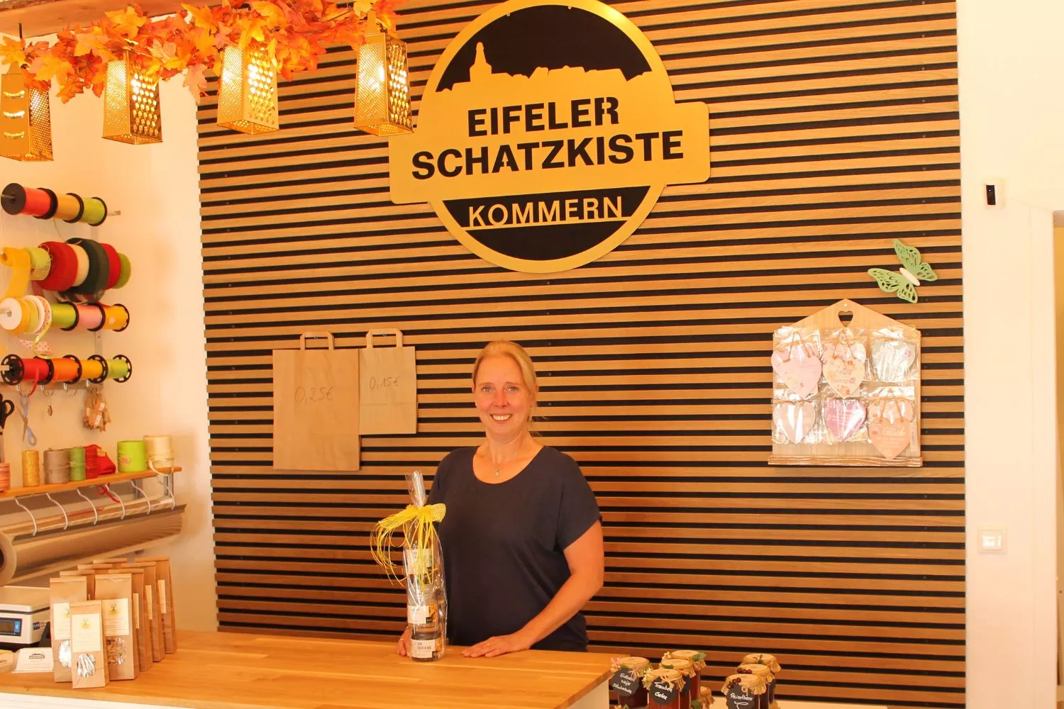 Inhaberin der Eifeler Schatzkiste an der Theke unter dem Logo – herzlich willkommen zum Vorbeikommen